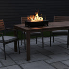 Apollo Tabletop Fireplace with flames on a patio area with chairs and cushions.