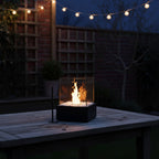 Fire pit on a wooden table with string lights in the background