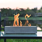 Concrete fire pit with flames on a blurred outdoor background
