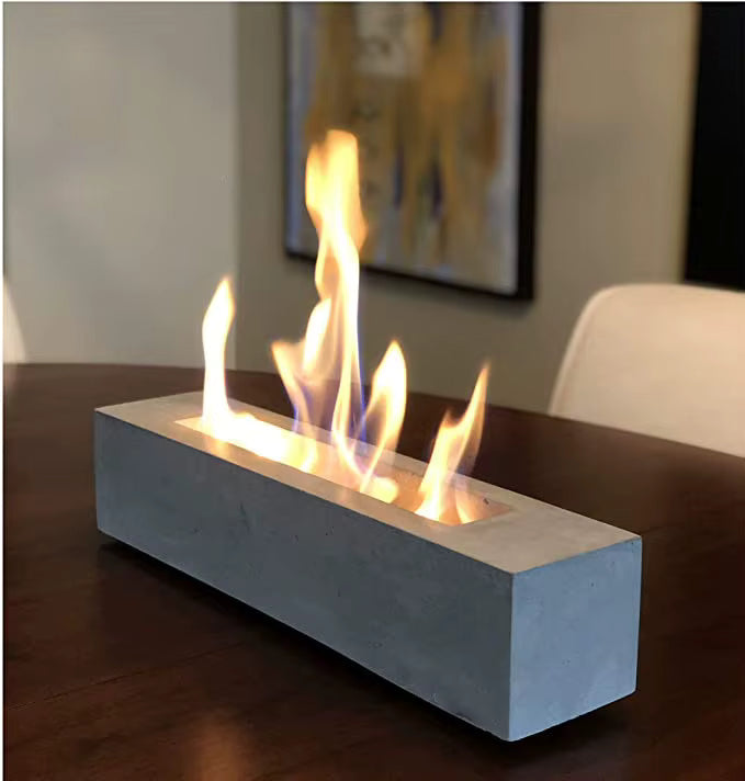 Modern concrete fireplace insert with flames on a wooden surface.