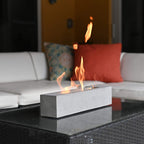 Fire pit on a table with a couch and pillows in the background