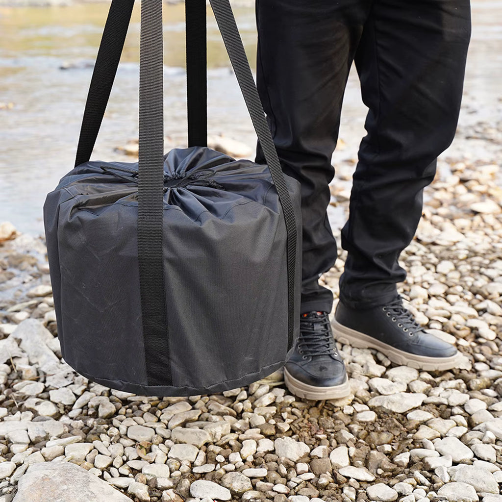Person holding provided black duffel bag with vulcan fireplace on a rocky ground