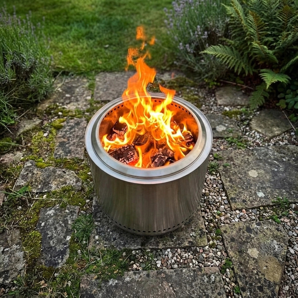 Vulcan Fireplace with flames burning on a stone patio surrounded by greenery